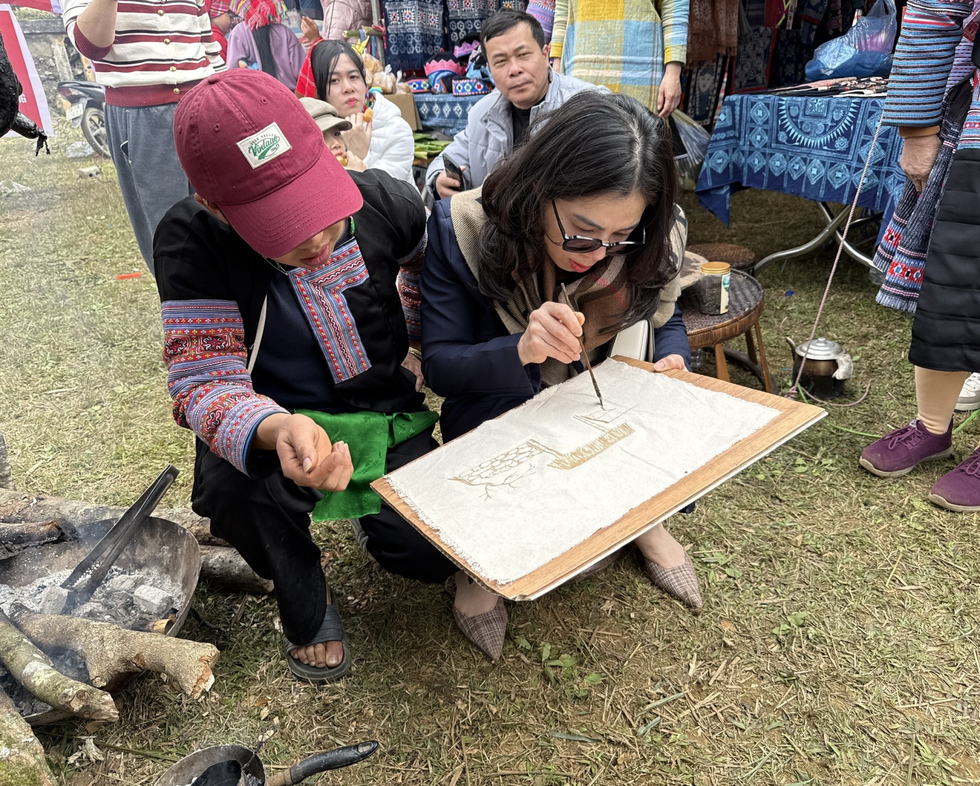 Du khách trải nghiệm vẽ tranh sáp ong tại lễ hội.