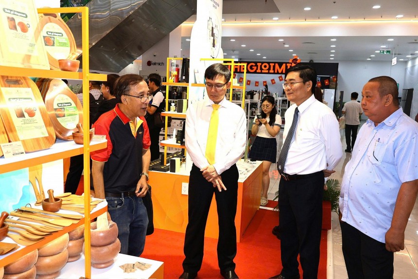 Ông Nguyễn Nhật Chương, Giám đốc Công ty TNHH Thương mại Dịch vụ KingWood (ngoài cùng, bên phải) giới thiệu sản phẩm gia dụng, dụng cụ nhà bếp bằng gỗ đạt chứng nhận OCOP đến quý đại biểu